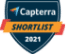 Alt text: A badge-shaped logo with a dark blue background displays the word "Capterra" at the top next to a small multicolored triangular icon. Below, an orange banner features the word "SHORTLIST" in bold white letters, and the year "2021" is shown at the bottom in white text.